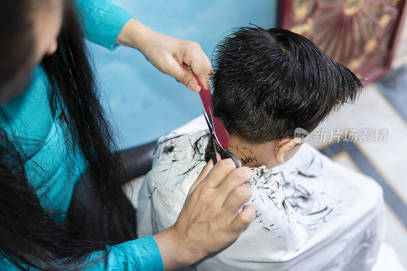 Mother cutting child's hair at home.